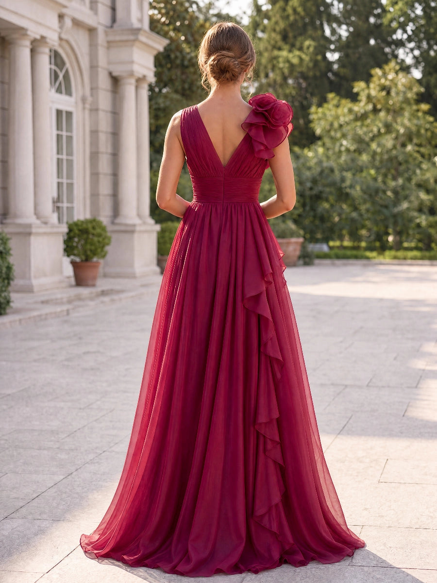 Vedress burgundy chiffon evening gown,back view deep V‑back,one shoulder cascading ruffle detail,pleated waist,full sweeping maxi skirt,stone courtyard background