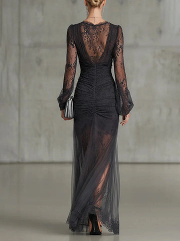 Back view of Vedress black lace evening dress showing a sheer lace back, fitted ruched waist and lace-trimmed floor-length skirt.