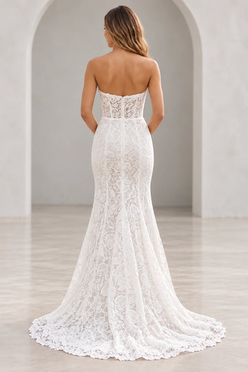 Vedress lace mermaid wedding dress with a low sheer back, visible boning, central zipper and scalloped lace sweep train, back view