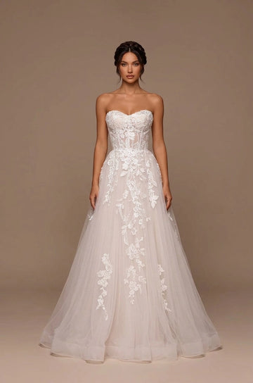 Ivory A-line wedding dress featuring a strapless sweetheart neckline, sheer corset-style bodice, floral lace appliques and flowing tulle skirt.