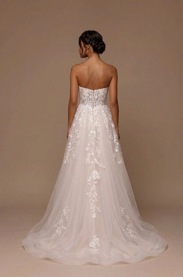 Back view of ivory strapless lace wedding dress with decorative button detailing, floral embroidery, flowing A-line skirt and soft sweep train.