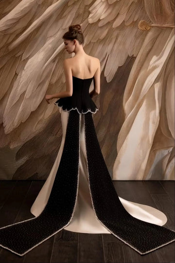 Black and white evening dress with strapless back and long black cape-style trailing panels by Vedress