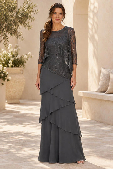 Dark gray mother of the bride dress featuring round neckline, shimmering lace overlay, sheer three-quarter sleeves and cascading layered floor-length skirt