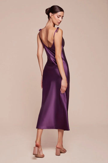 Back view of eggplant satin-look bridesmaid dress featuring a low V-back, delicate shoulder ties, softly draped fabric, and midi-length skirt.