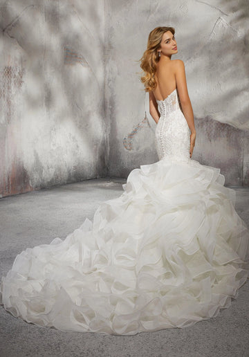 Back view of ivory mermaid bridal gown featuring low open button back, intricate lace detailing and voluminous ruffled wedding train