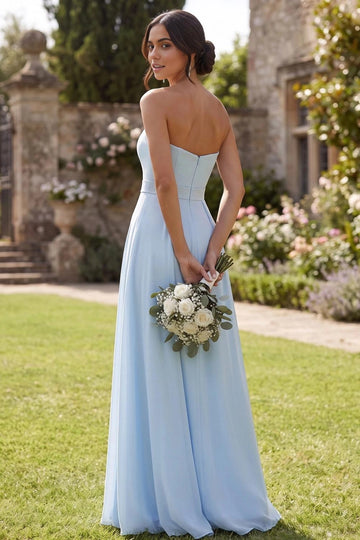 Back view of light blue strapless bridesmaid dress featuring a straight back neckline, center-back zipper, fitted waistband, and flowing A-line maxi skirt.