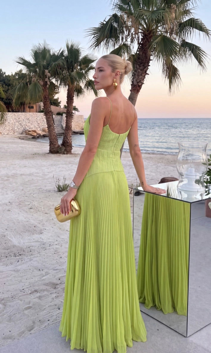 Back view of lime green prom dress featuring thin spaghetti straps, low scoop neckline, vertically pleated fitted bodice, asymmetric waist seam, and long pleated skirt.