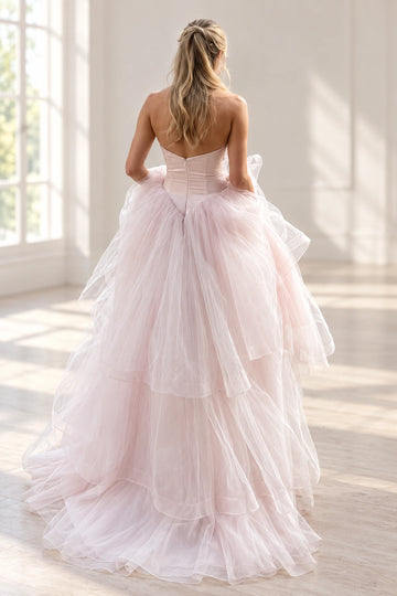Back view of a Vedress pink wedding dress with a dipped satin bodice, center-back zipper, pointed waist and cascading tulle ruffles.