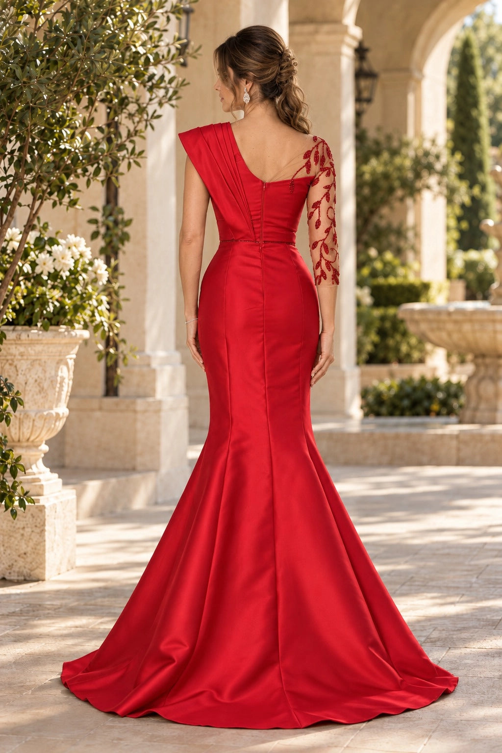 Back view of red mermaid mother of the bride gown featuring asymmetric V-back, center zipper, sheer beaded sleeve and flared sweep train.