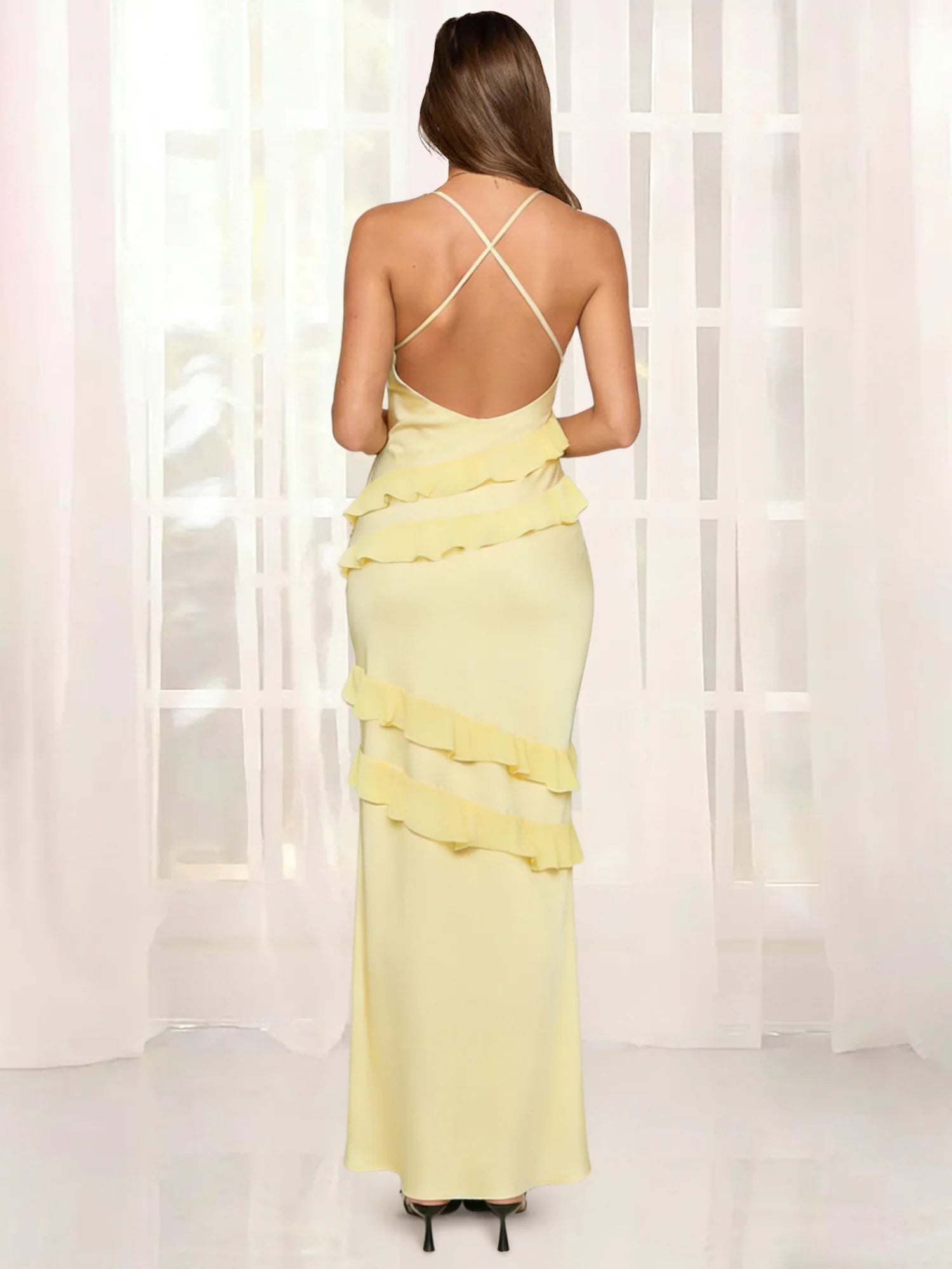 Back view of butter yellow backless maxi dress with crisscross straps, open back design, and layered ruffle details