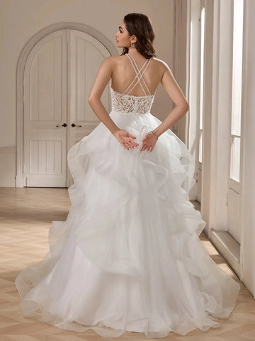Back view of Vedress ruffled wedding dress with crossed spaghetti straps, a low V-shaped lace back and a full layered tulle skirt.