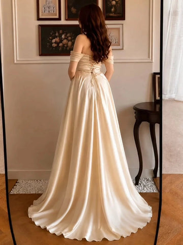 Back view of a champagne satin Vedress prom dress with a lace-up corset back, draped off-shoulder sleeves and a flowing sweep train.
