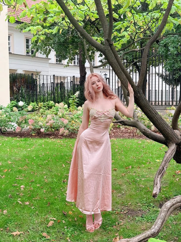 Front view of Vedress pink satin wedding guest dress with a lace neckline, bow detail and ankle-length A-line skirt, shown outdoors.