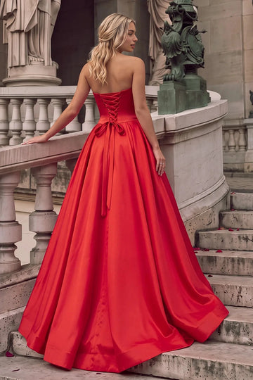 Back view of Vedress red satin A-line prom dress featuring a corset lace-up back, trailing bow ties and a full floor-length skirt.