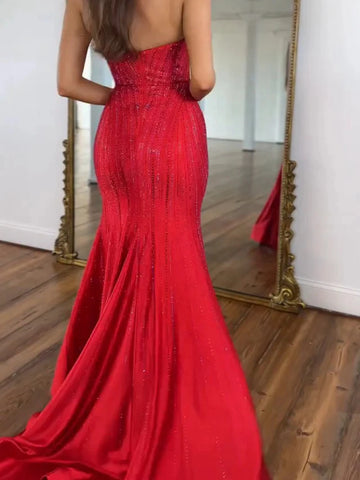 Vedress red mermaid prom dress with a straight-across low back, flowing lines of sparkling embellishments, and a sweep train, back view.