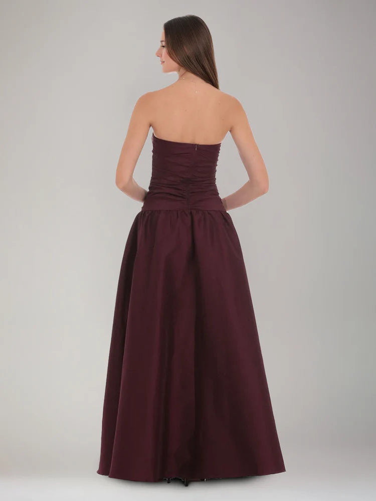 Back view of burgundy strapless satin formal dress with ruched bodice, center zipper, and full A-line skirt