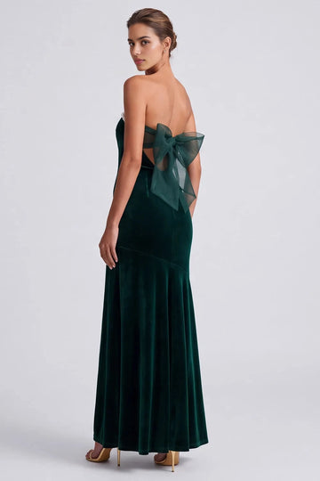 Back view of Vedress green velvet evening dress featuring a low open back, sheer horizontal bands and an oversized translucent bow.