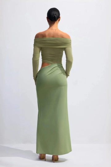 Back view of sage green wedding guest dress with off-shoulder long sleeves, waist cutout and floor-length skirt
