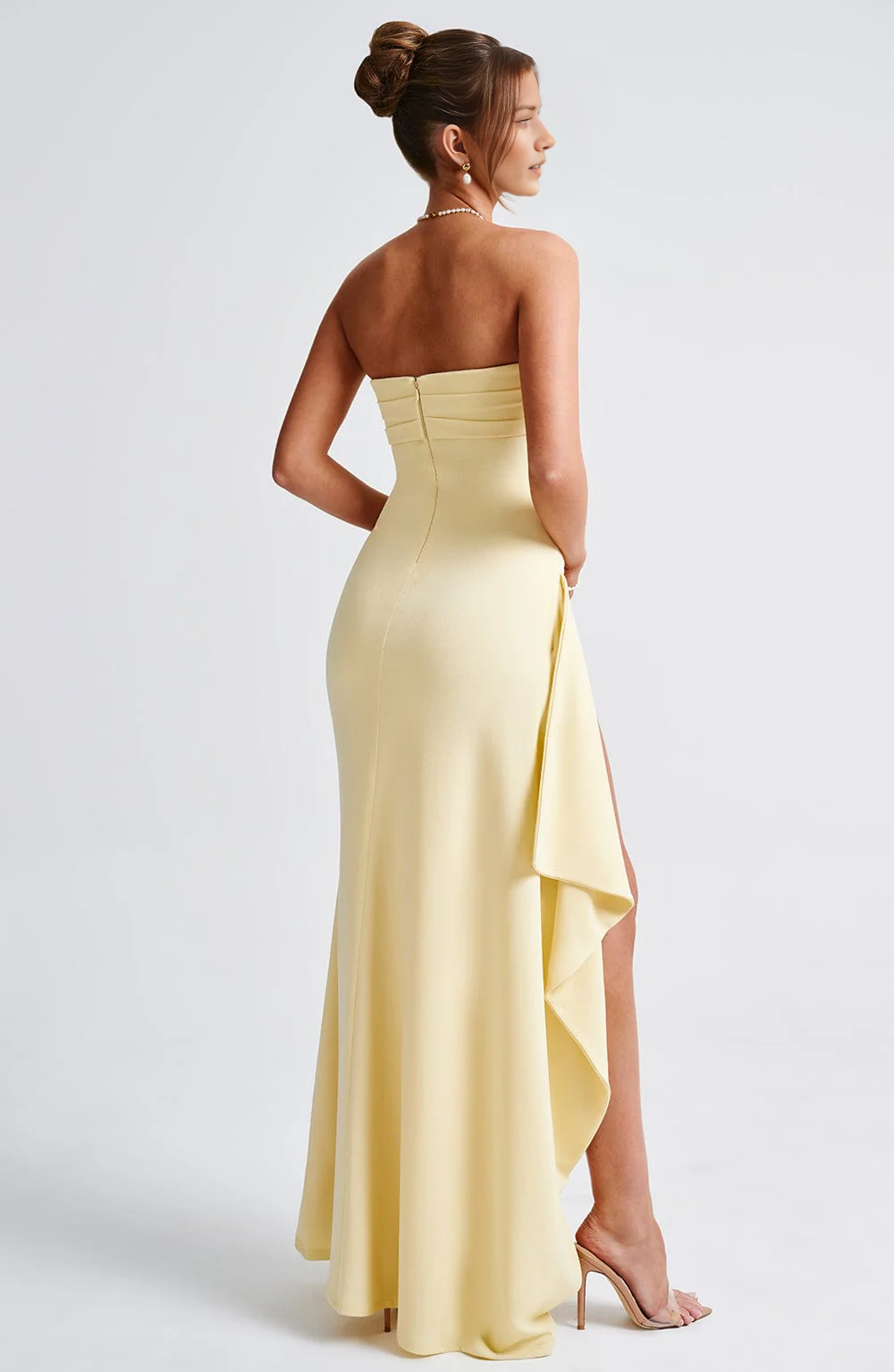 Open-back strapless formal gown with center zipper closure, side drape, sheath silhouette, and elegant floor-length skirt