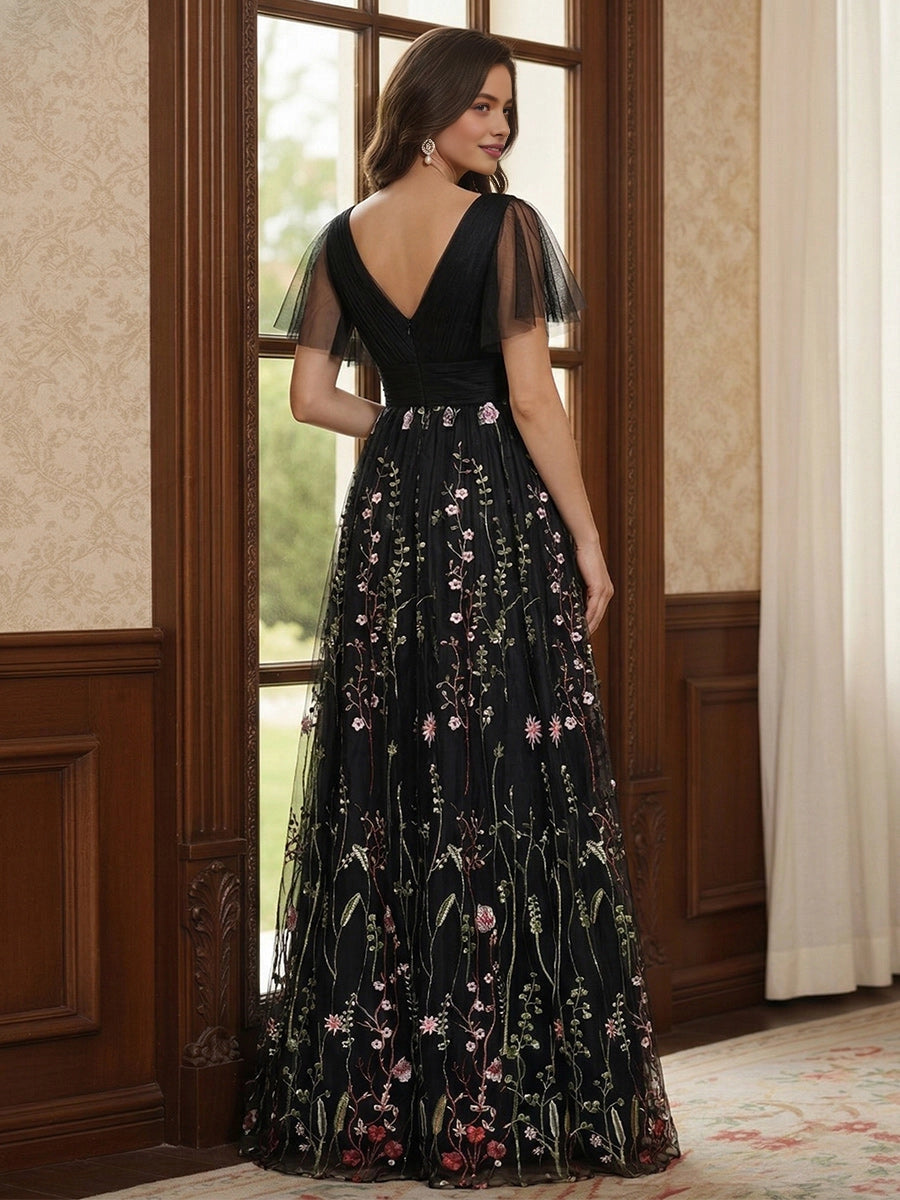 Model wearing vedress black floral embroidered mother of bride dress deep v‑back long formal gown rear view