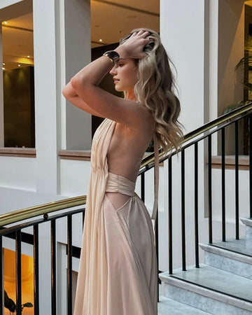 Back view of Vedress champagne evening dress showing an open back, side waist cutouts and a softly draped skirt.
