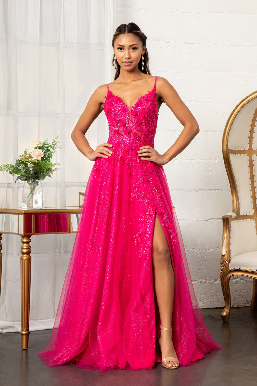 Vestido largo de fiesta y para invitadas a boda, de tul con purpurina fucsia, corte A, tirantes finos, escote en V, apliques florales 3D y abertura alta.