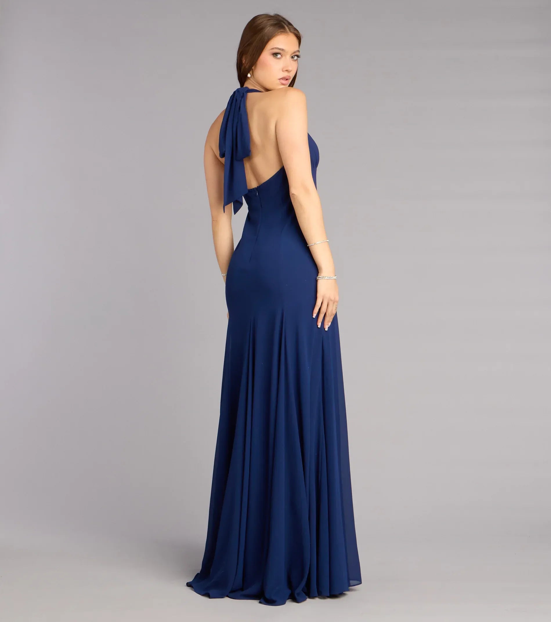 Back view of open back halter chiffon evening dress with tie detail, zipper closure, and flowing A-line skirt
