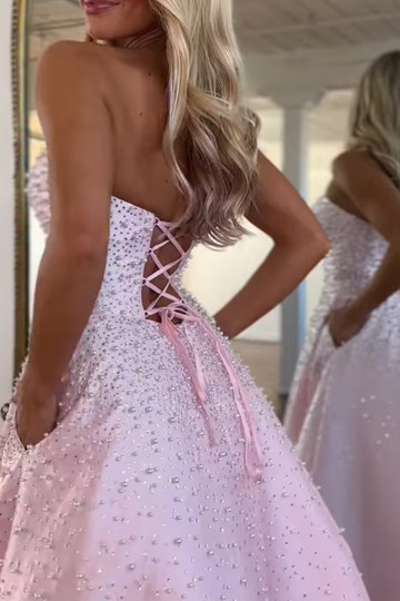 Vestido largo de satén con escote corazón sin tirantes, pedrería y bolsillos laterales, ideal para fiestas de graduación y como invitada de boda