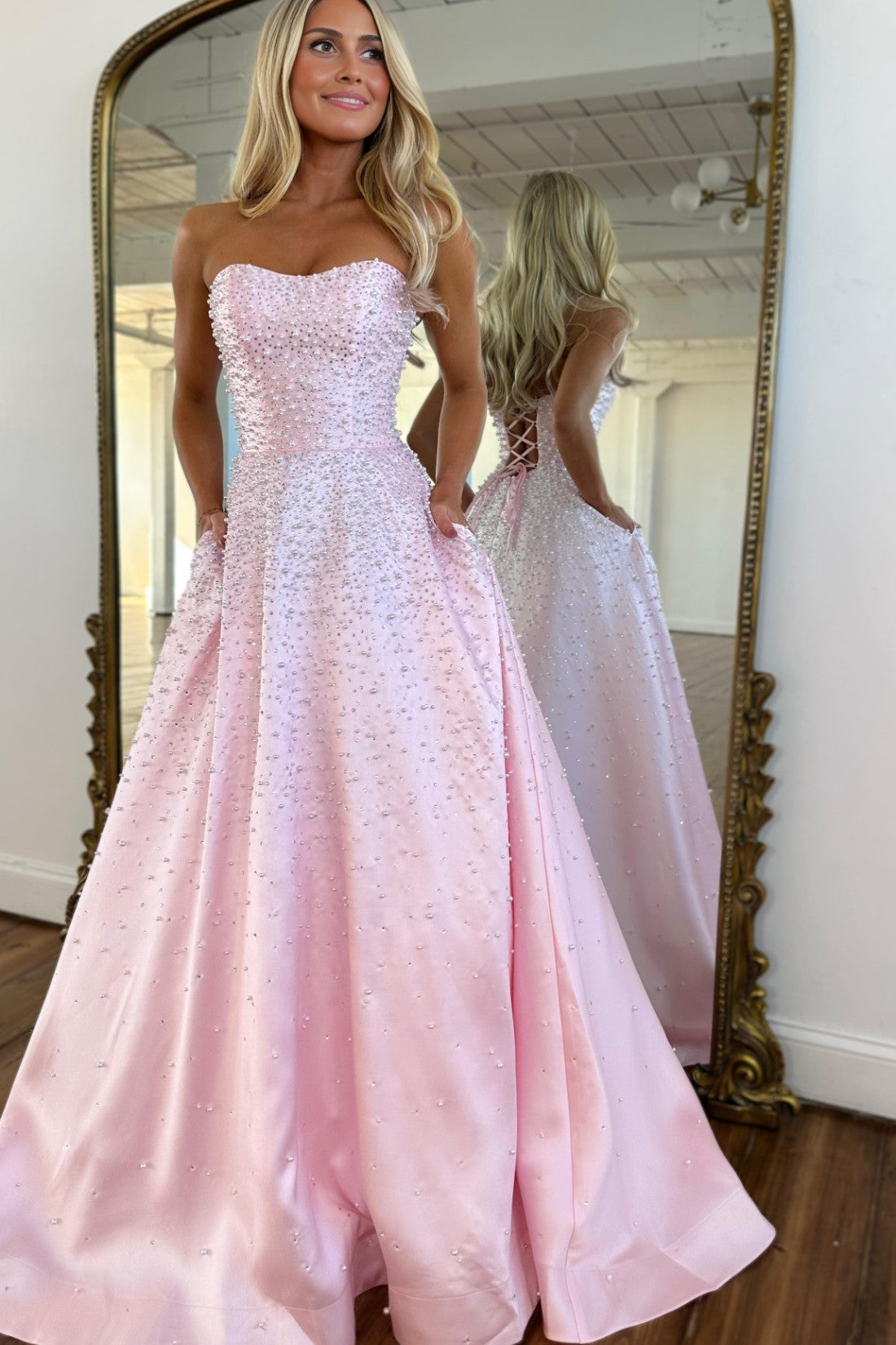 Vestido largo de satén con escote corazón sin tirantes, pedrería y bolsillos laterales, ideal para fiestas de graduación y como invitada de boda