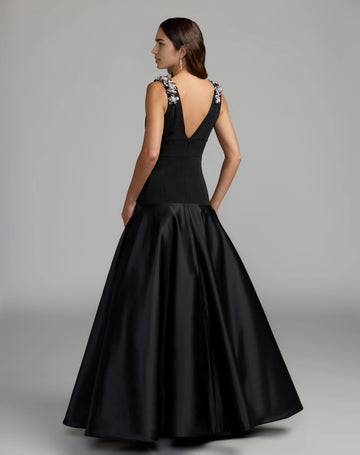 Back view of black A-line wedding guest dress featuring a deep V-back, silver floral shoulder appliqués, concealed zipper, and flowing satin-look skirt.