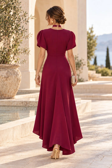 Back view of burgundy mother of the bride dress featuring a closed zipper back, short puff sleeves, fitted waist and flowing high-low skirt.