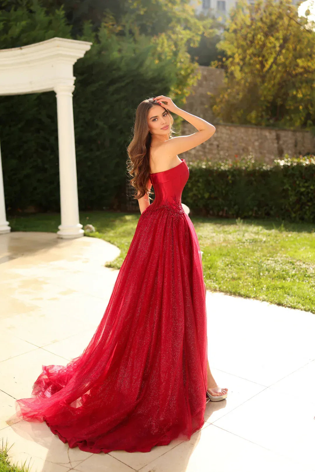 Open-back strapless formal gown with glitter tulle skirt, structured bodice, appliqué waist detail, and elegant train by Vedress