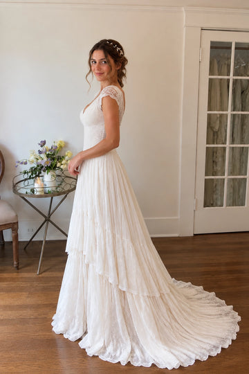 Back view of Vedress lace wedding dress featuring a scalloped scoop back, center zipper, pointed waist and cascading lace tiers with a train