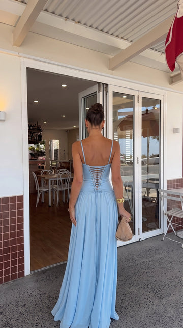 Back view of light blue prom dress featuring thin adjustable shoulder straps, crisscross lace-up corset closure, V-shaped waist, and gathered A-line maxi skirt.