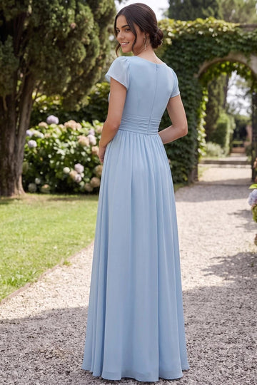 Back view of light blue bridesmaid dress featuring a modest rounded neckline, short cap sleeves, center-back zipper, ruched waist, and flowing A-line skirt.