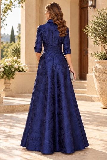 Back view of navy blue mother of the bride gown with high collared back, floral textured pattern, three-quarter sleeves, fitted waistband and flowing A-line skirt