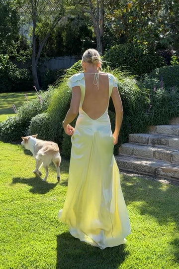 Pale yellow wedding guest dress with low open back and flowing floor length skirt by Vedress