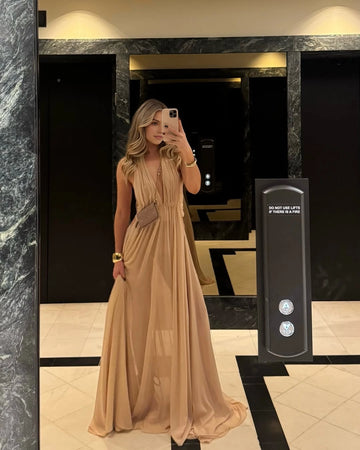 Vedress champagne evening dress with a plunging V-neck, sleeveless gathered bodice and flowing floor-length skirt.