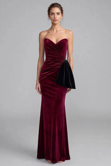 Vedress burgundy velvet evening dress with a strapless sweetheart neckline, diagonal ruching and a contrasting black side bow accent.